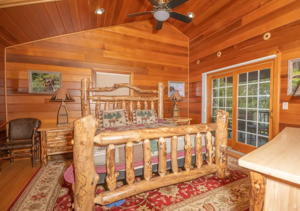 Bedroom with moose-motif bedding and wood ceiling